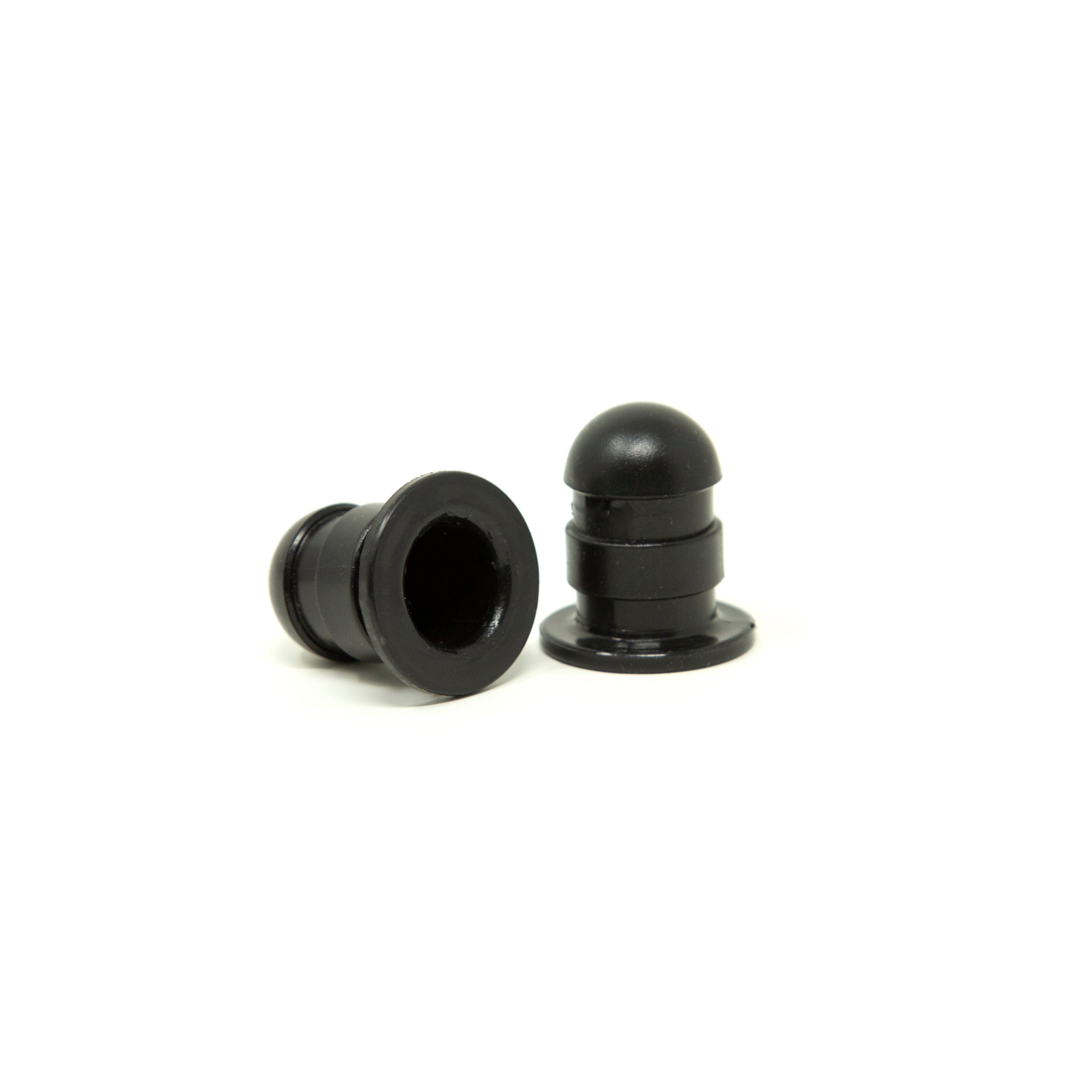 One black pole cap sitting up straight and one black pole cap lying on its side.