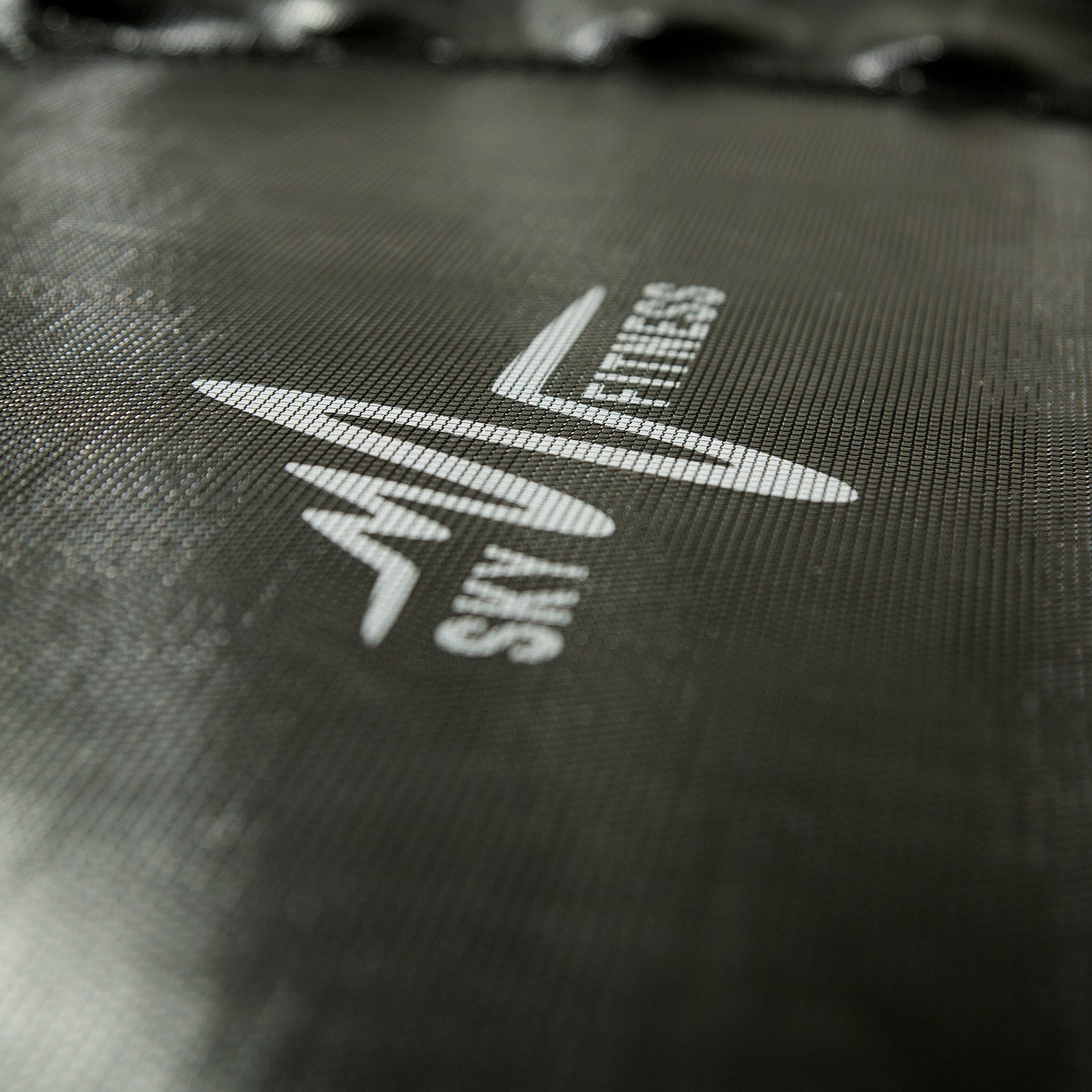 A close-up view of the white SkyFitness logo on the black jump mat.