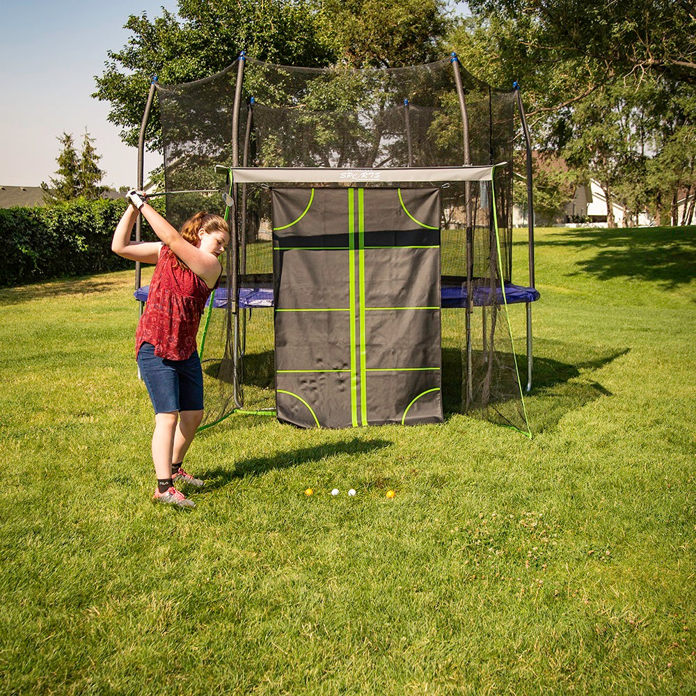 Girl swinging back golf club to hit golf ball.