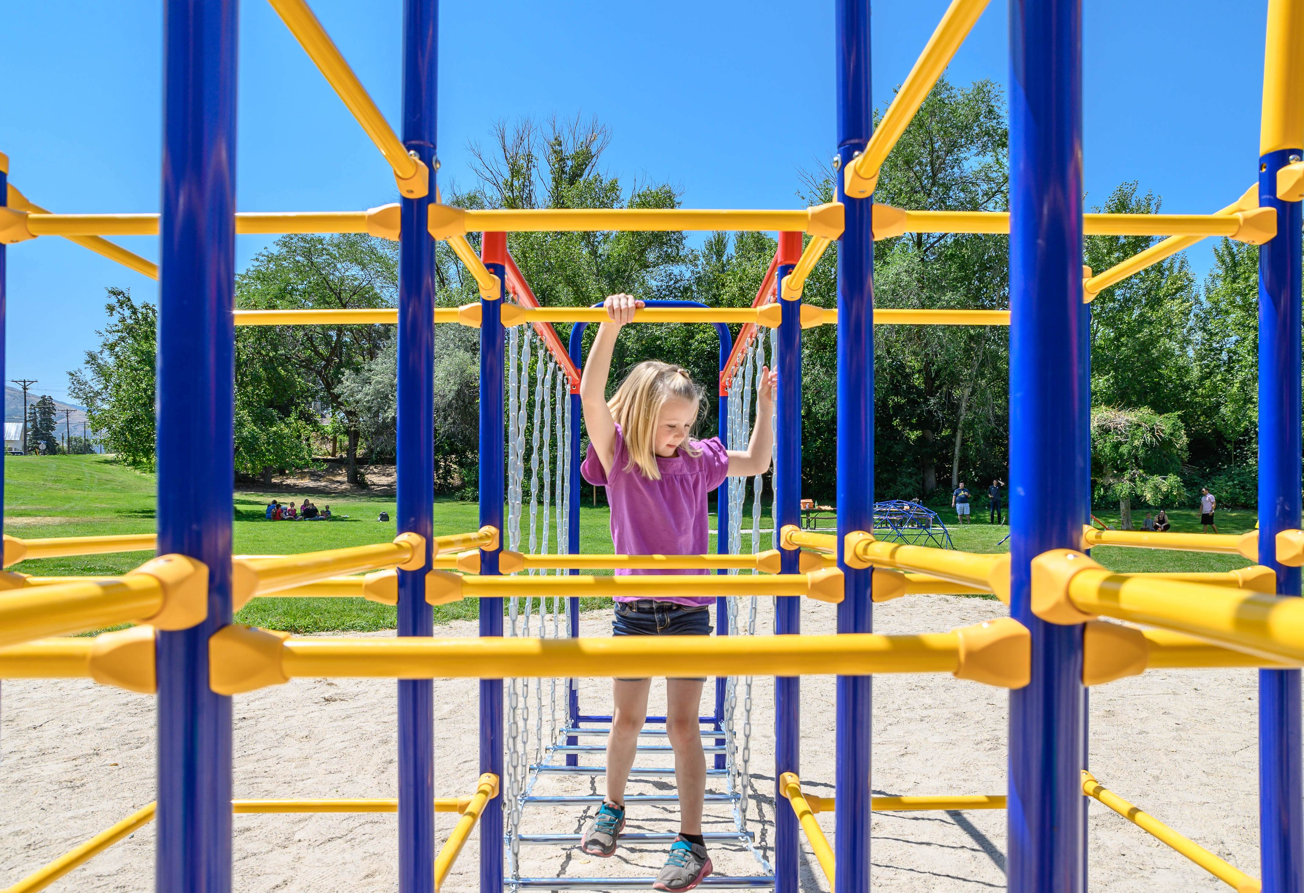 A view of a girl climbing from the bridge to the jungle gym base.