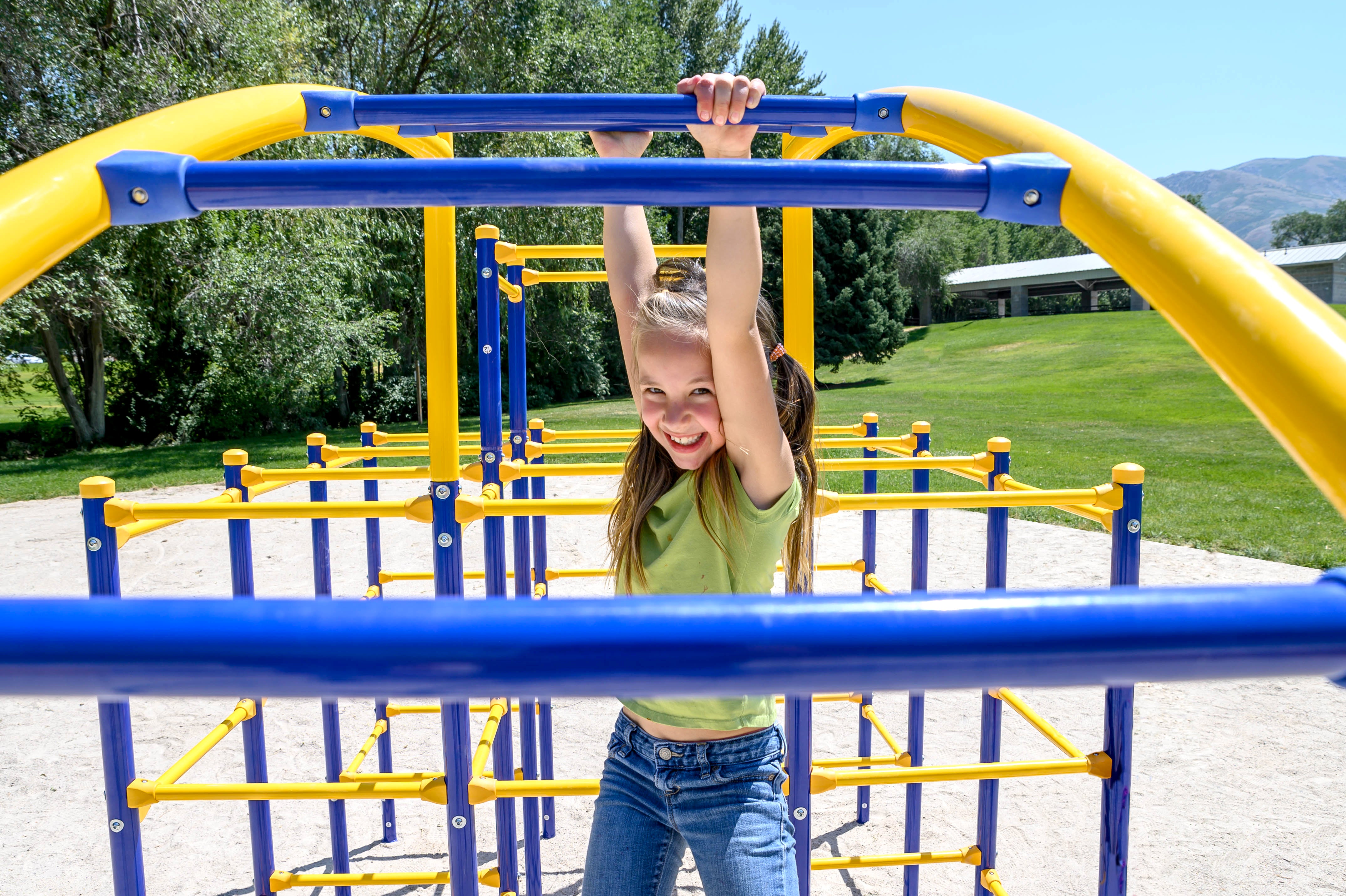 Girl smiles while hanging from the climber ladder.