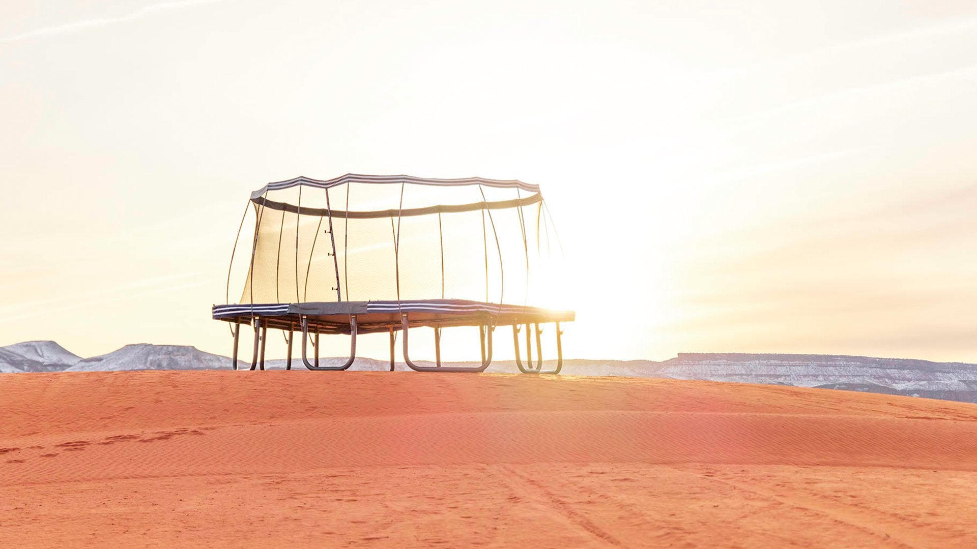 A rectangle premium trampoline in a backyard with a sunset in the sky.. 