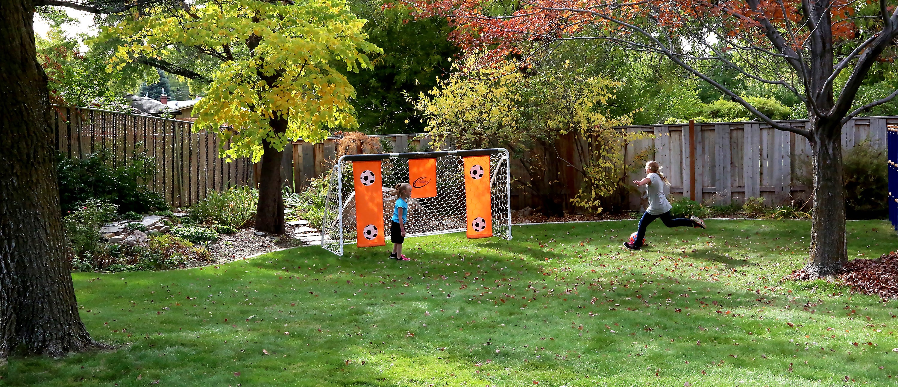 A group of children kick a soccer ball around in front of the goal.