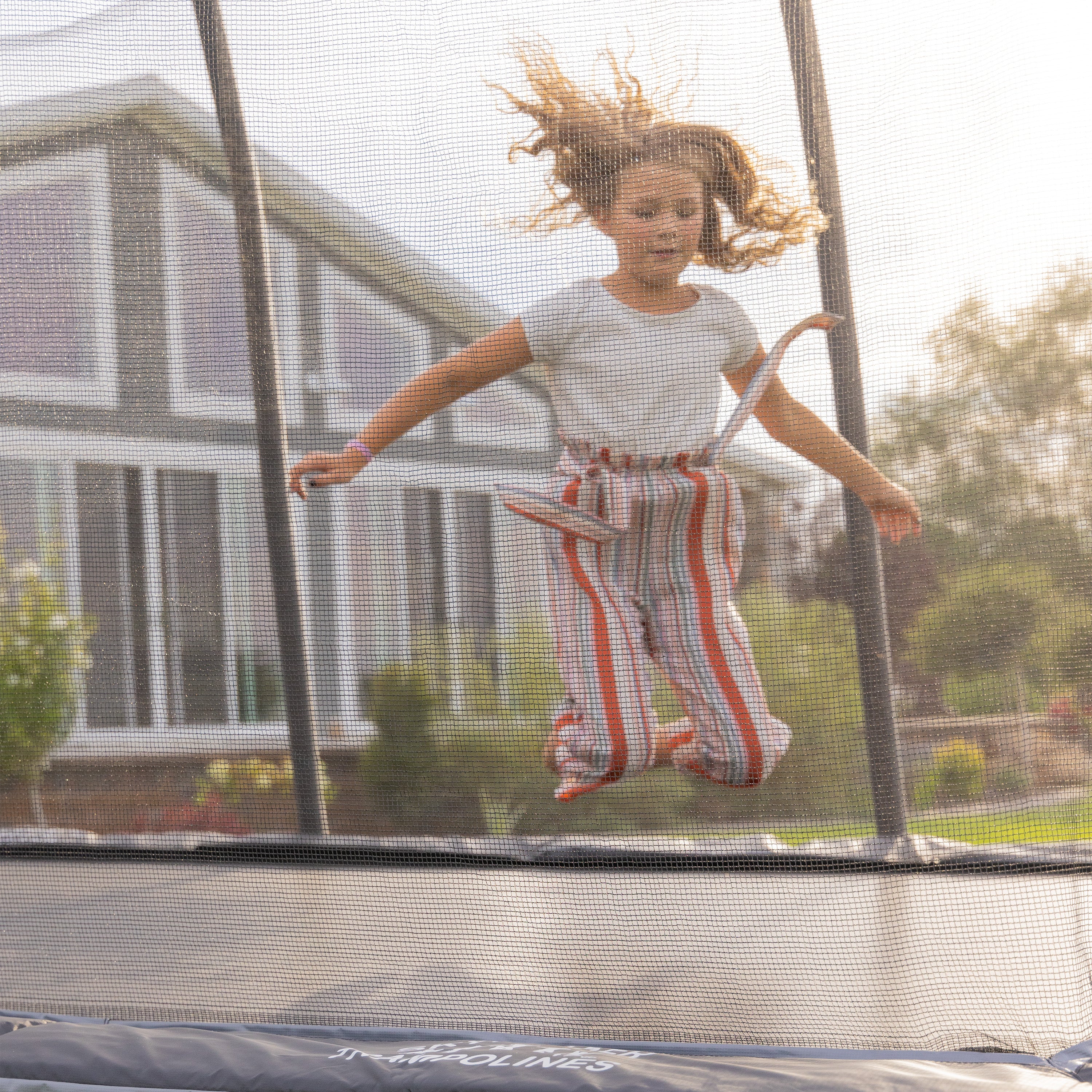 Girl bounces on her knees on the 9 by 15-foot Epic Trampoline. 