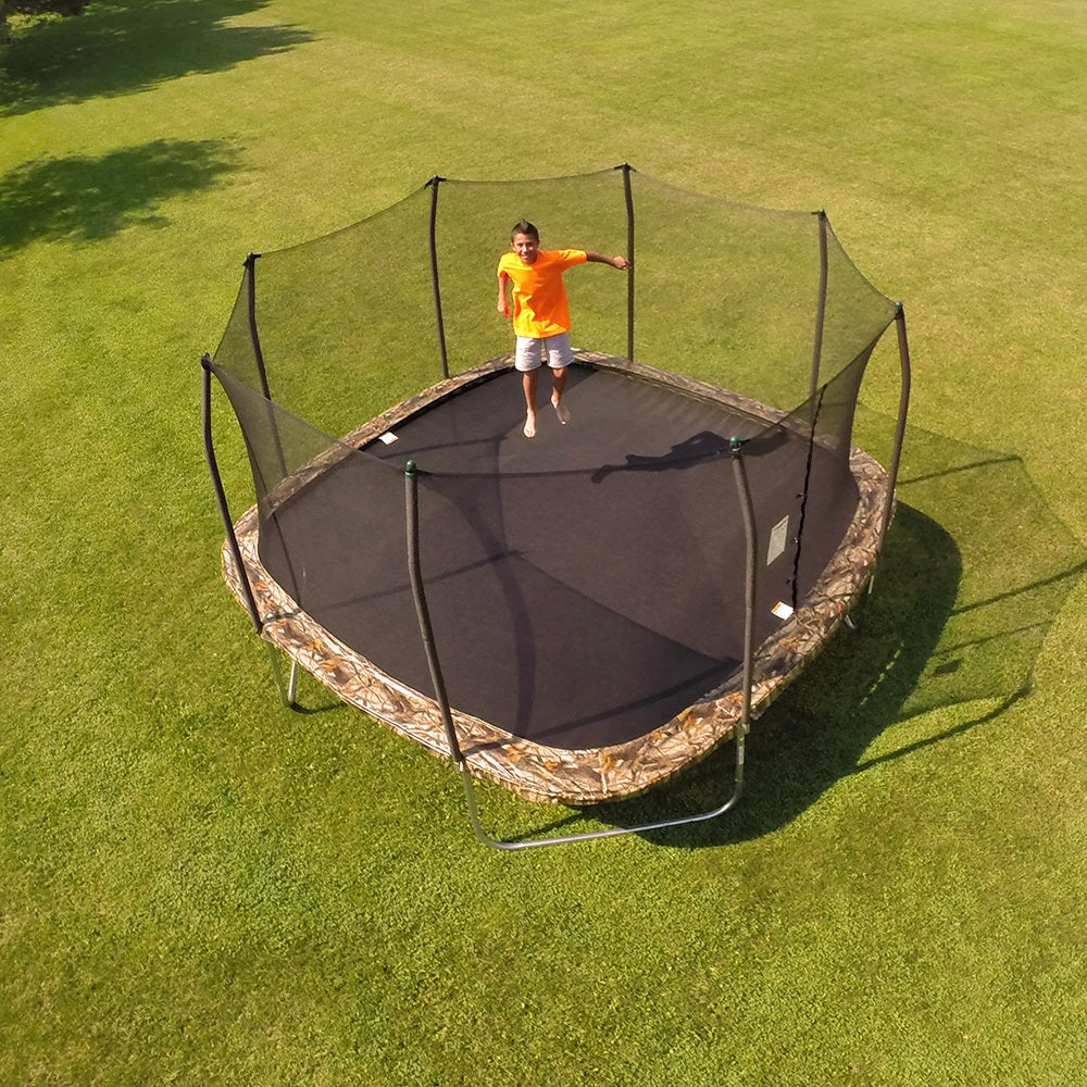 Teenage boy jumps on the 14-foot square trampoline with camouflage spring pad. 