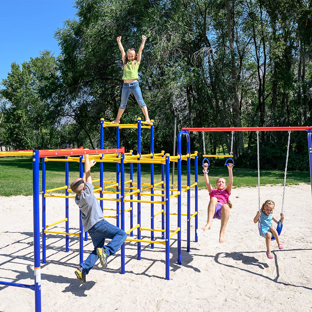 Two girls swing on the Swing Set, a boy hangs on the monkey bars, and 1 girl stands triumphantly on the Jungle Gym.