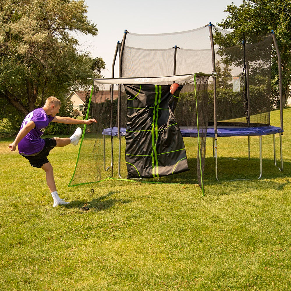 Teenage boy kicks football at the Multi-Sport Training Net. 