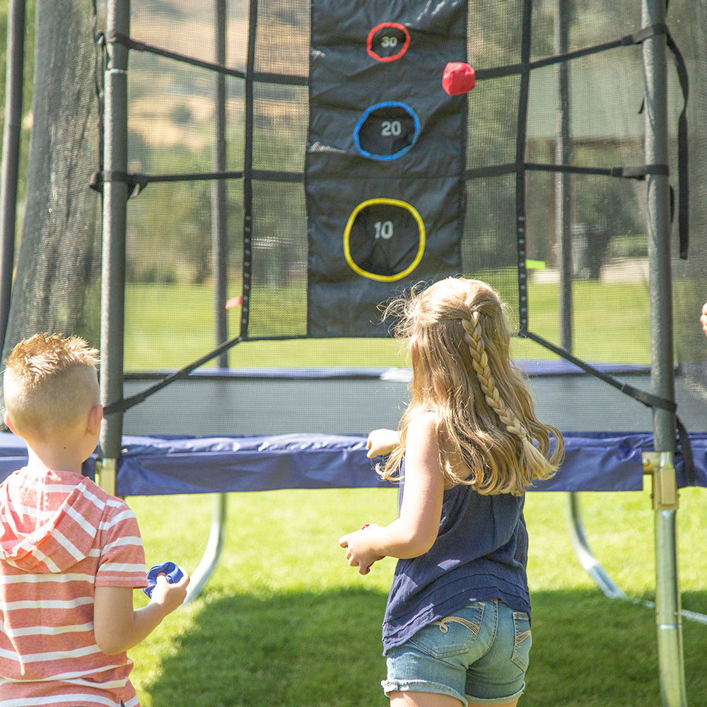 Two young kids throw bean bags at the Triple Toss Game. 