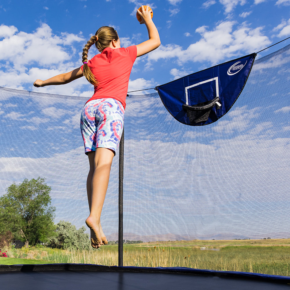 Young girl jumps up in the air to dunk the basketball. 