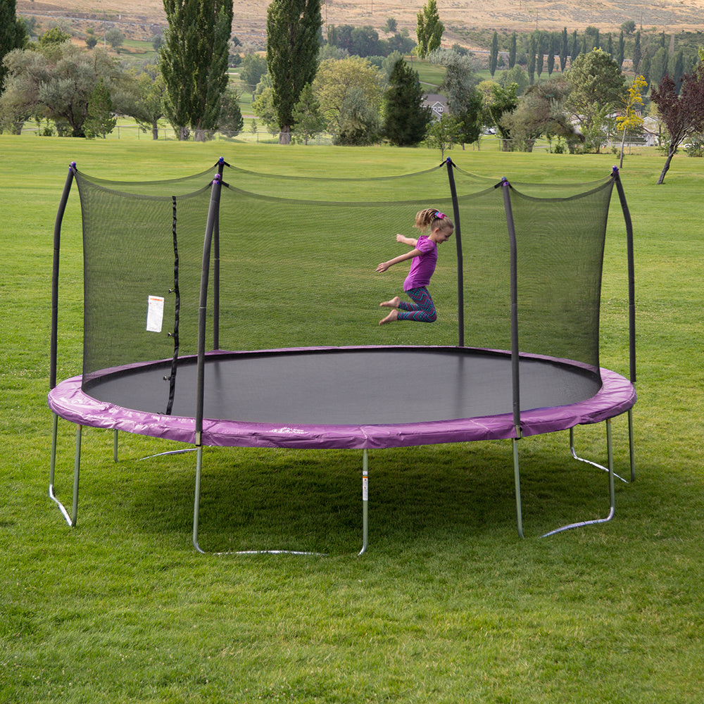 Little girl bounds around on the 17-foot oval trampoline with purple spring pad. 